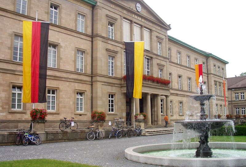 Outside view of University of Tubingen in Germany. There is a fountain outside and german flag is hanging ouside